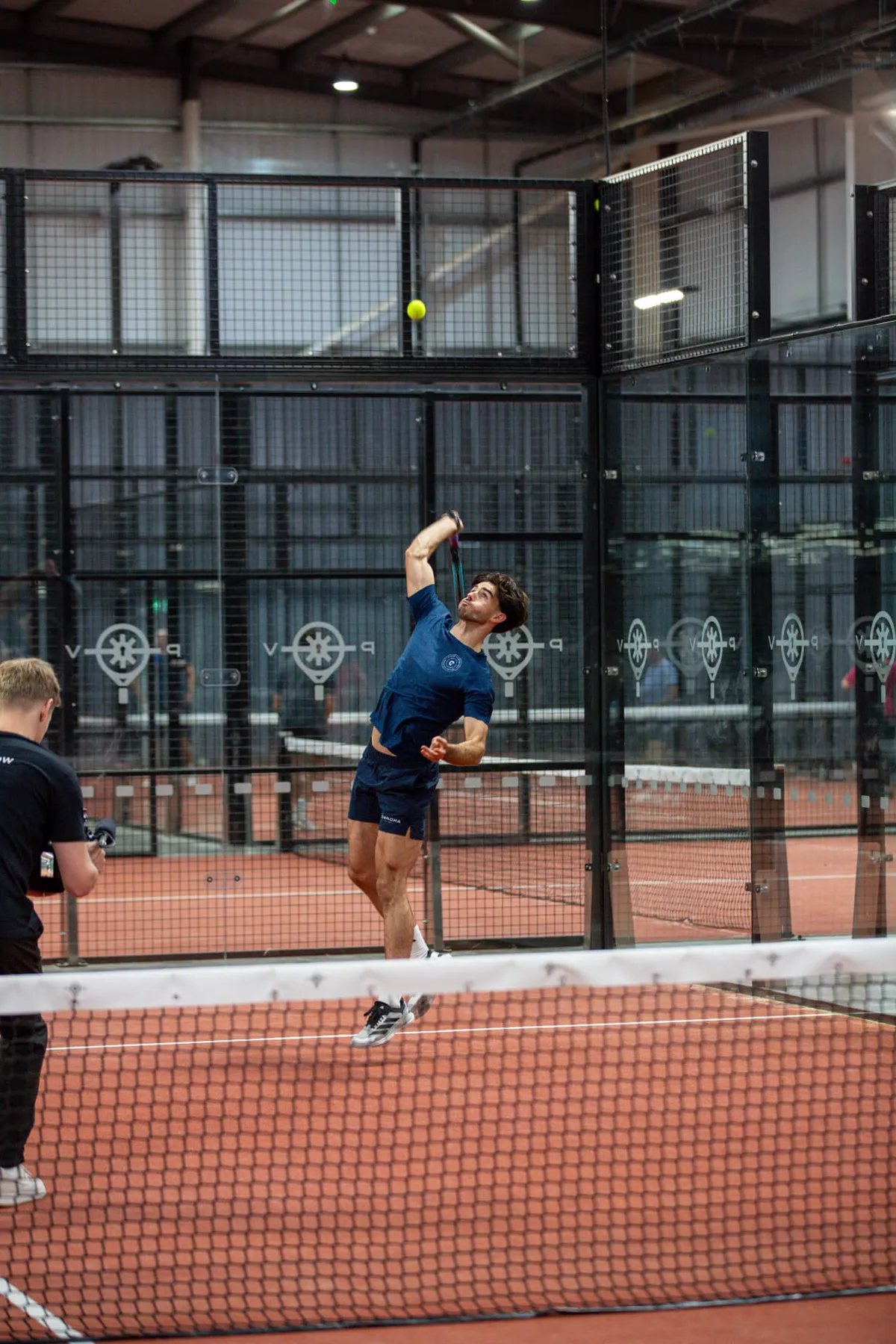 Coach Kyle hitting an overhead smash on a padel court
