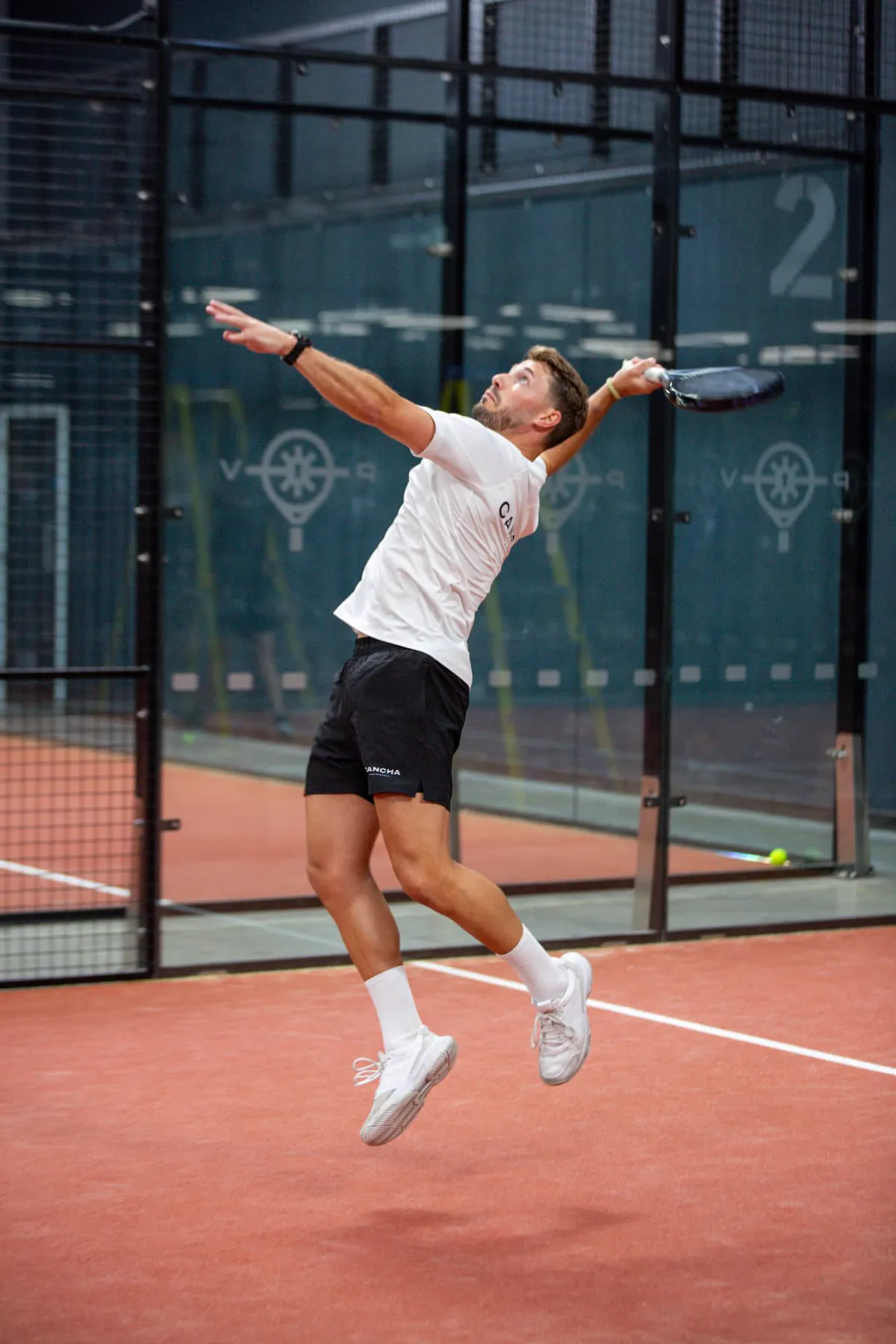 Coach Steve jumping for an overhead on a padel court